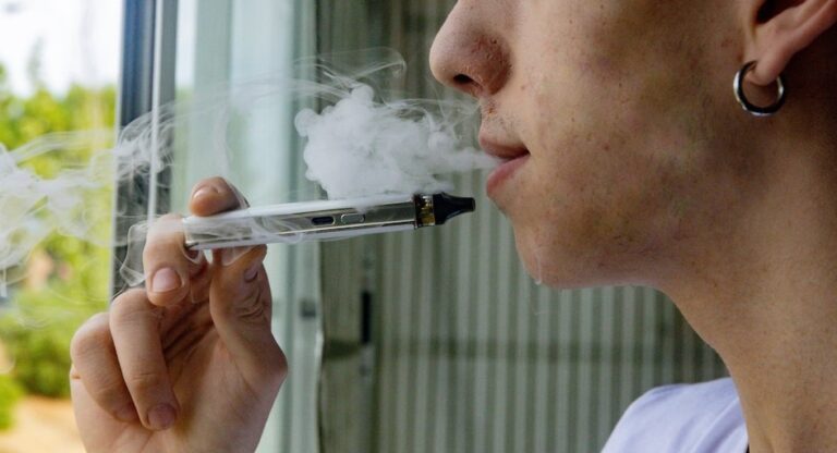 Vapeadores y bolsitas de nicotina sobre una mesa, con un documento oficial de fondo